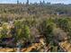 An aerial view shows a home surrounded by lush trees with the cityscape beyond at 725 Glengary Ne Way, Atlanta, GA 30342