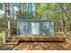 Quaint backyard shed featuring siding, a deck, and a white door, nestled among trees at 195 Creekside Way, Mcdonough, GA 30252
