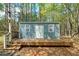 Charming blue shed with deck and surrounding trees in a wooded backyard at 195 Creekside Way, Mcdonough, GA 30252