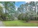 Landscaped front yard with a charming ranch-style home nestled among trees and flowering plants at 195 Creekside Way, Mcdonough, GA 30252