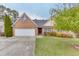 Charming brick home featuring a well-manicured lawn, mature trees, and attached two-car garage at 802 Towering Pine Trl, Lawrenceville, GA 30045