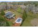 Aerial view of a property with a tennis court, swimming pool, and wooded surroundings at 1483 Jones Rd, Roswell, GA 30075