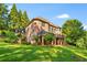 Back exterior showcasing an expansive lawn, covered deck, brick facade and mature landscaping at 1483 Jones Rd, Roswell, GA 30075