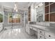 Bright bathroom featuring a glass shower, dual vanities with marble countertops, and large windows at 1483 Jones Rd, Roswell, GA 30075