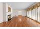 Open living room featuring gleaming hardwood floors, fireplace, and large windows with elegant drapes at 9095 Cedar Grove Rd, Fairburn, GA 30213