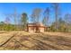 Charming outbuilding nestled on a large lot with a covered porch, surrounded by mature trees and an open field at 9095 Cedar Grove Rd, Fairburn, GA 30213