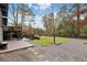 Expansive backyard featuring a stone patio with seating, lush lawn, mature trees, and a charming two-story deck at 3473 Regalwoods Dr, Atlanta, GA 30340