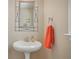 Bathroom featuring pedestal sink with decorative mirror and an orange towel at 4950 Luke Dr, Cumming, GA 30040