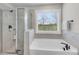 Bathroom featuring glass shower, soaking tub, and a bright window at 708 Chipping Sparrow St, Canton, GA 30115