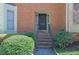 Charming brick townhome entry with black front door, mature shrubs, and welcoming steps at 1363 Sheffield Glen Way, Atlanta, GA 30329