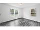 Bright bedroom featuring hardwood floors, fresh white paint, and natural light from two large windows at 1752 Atherton Dr, Decatur, GA 30035