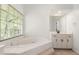Bright bathroom featuring large soaking tub, picture window, and vanity sink at 2731 Old Coach Rd, Duluth, GA 30096