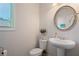 A quaint powder room with a pedestal sink, decorative mirror, and natural light from the window at 1151 Wisteria Sw Dr, Mableton, GA 30126