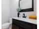 Stylish powder room with dark wood vanity, quartz countertop, dark faucet and decorative mirror at 5210 Davenport Pl, Roswell, GA 30075