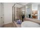 Bathroom featuring tiled shower and soaking tub with neutral tile throughout at 5210 Davenport Pl, Roswell, GA 30075