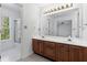 Bright bathroom with double sinks, a large mirror, and a view into the shower behind a glass door at 165 River Ridge Ln, Roswell, GA 30075