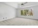Bright bedroom with a vaulted ceiling, a ceiling fan, neutral carpeting, and a large window overlooking a leafy yard at 165 River Ridge Ln, Roswell, GA 30075
