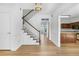 Bright foyer featuring hardwood floors, a staircase with white railing, and views into the kitchen at 165 River Ridge Ln, Roswell, GA 30075