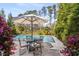 Backyard pool area with a dining table and chairs, and surrounded by lush greenery and flowers at 2033 Lee Se Rd, Smyrna, GA 30080