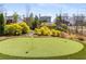 Backyard putting green with artificial turf, surrounded by manicured landscaping and beautiful trees at 2033 Lee Se Rd, Smyrna, GA 30080