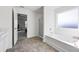 Bright bathroom featuring a soaking tub, gray tile flooring, and an open doorway to an office at 469 Ralph Still Rd, Dacula, GA 30019