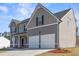 Beautiful house with gray siding, white garage doors, and a well-maintained lawn, set against a bright sky at 469 Ralph Still Rd, Dacula, GA 30019