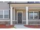 Inviting front entrance with gray door, white columns, brick accents, and neatly landscaped flower beds at 469 Ralph Still Rd, Dacula, GA 30019