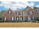 Stately brick home with a symmetrical facade, manicured landscaping, and a covered front porch at 4020 Inman Park Lane, Buford, GA 30519