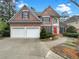 Charming two-story brick home with a manicured lawn, a red door, a two-car garage, and blue window shutters at 3083 Milledge Gate Se Ct, Marietta, GA 30067