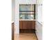 Stylish bar area featuring wood cabinets, mirrored backsplash, and open shelving for showcasing glassware at 5245 Kenbrook Way, Sandy Springs, GA 30327