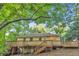 Back of house with wooden deck and stairs leading to yard shaded by mature trees at 656 Channing Nw Dr, Atlanta, GA 30318