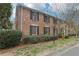 Side view of brick townhouse with black shutters, well maintained landscaping, and green lawn at 6700 Roswell Rd # 14C, Atlanta, GA 30328