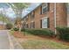 Side view of brick townhouse with black shutters, well maintained landscaping, and green lawn at 6700 Roswell Rd # 14C, Atlanta, GA 30328