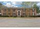 Charming brick townhouse featuring a well-maintained lawn, mature trees, and classic architectural details at 6700 Roswell Rd # 14C, Atlanta, GA 30328