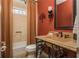 Unique bathroom features red walls, a stone countertop, decorative mirror and light fixture, and tiled shower at 275 Tynebrae Pl, Roswell, GA 30075