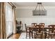 Elegant dining room features hardwood floors, wainscoting, a modern light fixture, and large window with natural light at 275 Tynebrae Pl, Roswell, GA 30075
