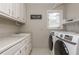 Laundry room features ample counter space, upper cabinets, a window, and a washer and dryer at 275 Tynebrae Pl, Roswell, GA 30075
