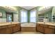 An angled view of a large bathroom with dual sinks and a central bathtub beneath a window at 1074 Whooping Creek Rd, Carrollton, GA 30116