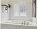 Bright bathroom featuring a white soaking tub with modern fixtures, plantation shutters, and decor at 1270 Smokehouse Trl, Cumming, GA 30041