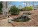 Relaxing water feature with a small pond and stone waterfall surrounded by lush greenery at 1270 Smokehouse Trl, Cumming, GA 30041