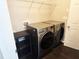 Modern laundry room with side-by-side washer and dryer and wire shelving at 2675 Sardis Chase Ct, Buford, GA 30519