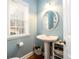 Charming powder room with pedestal sink, oval mirror, and natural light from the window at 4015 Embassy Way, Lilburn, GA 30047