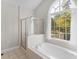 A tiled bathroom with a shower and a large tub under a large arched window at 152 Vinings Lake Ct, Mableton, GA 30126