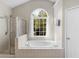 Bright bathroom featuring a tub under an arched window and separate shower at 152 Vinings Lake Ct, Mableton, GA 30126