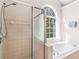 Bright bathroom with glass-door shower and a tub under an arched window at 152 Vinings Lake Ct, Mableton, GA 30126