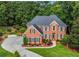 Beautiful aerial view of a brick home with a long driveway and mature trees in a serene setting at 2930 Monticello Dr, Cumming, GA 30041