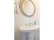 Elegant pedestal sink with a round mirror and soft lighting in this well-appointed bathroom at 4406 Kendall Way, Roswell, GA 30075