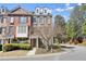 Brick townhome featuring manicured landscaping, a walkway, and a charming entrance, all under a bright, partly cloudy sky at 4406 Kendall Way, Roswell, GA 30075