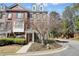Brick townhome featuring manicured landscaping, a charming entrance, all under a bright, partly cloudy sky at 4406 Kendall Way, Roswell, GA 30075