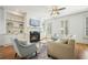 Bright living room features hardwood floors, fireplace with tv above, built-in shelves, and neutral furniture at 4406 Kendall Way, Roswell, GA 30075